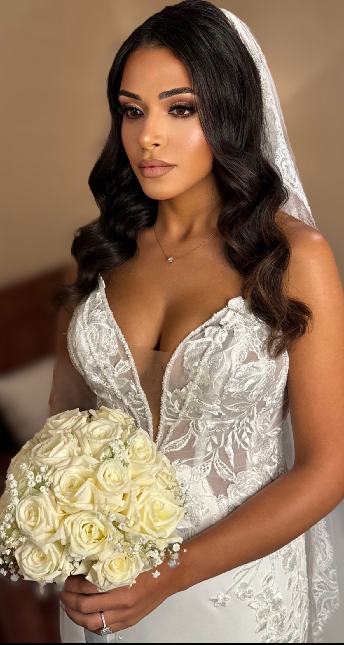 4e93bd093487d782d13cc81a82ea2fd32f5f31652d817ff769346ceb355e0af9 - Glam By Duaa Bridal hair and makeup contact — bride in a white lace gown holding white roses, long dark waves – Glam by Duaa
