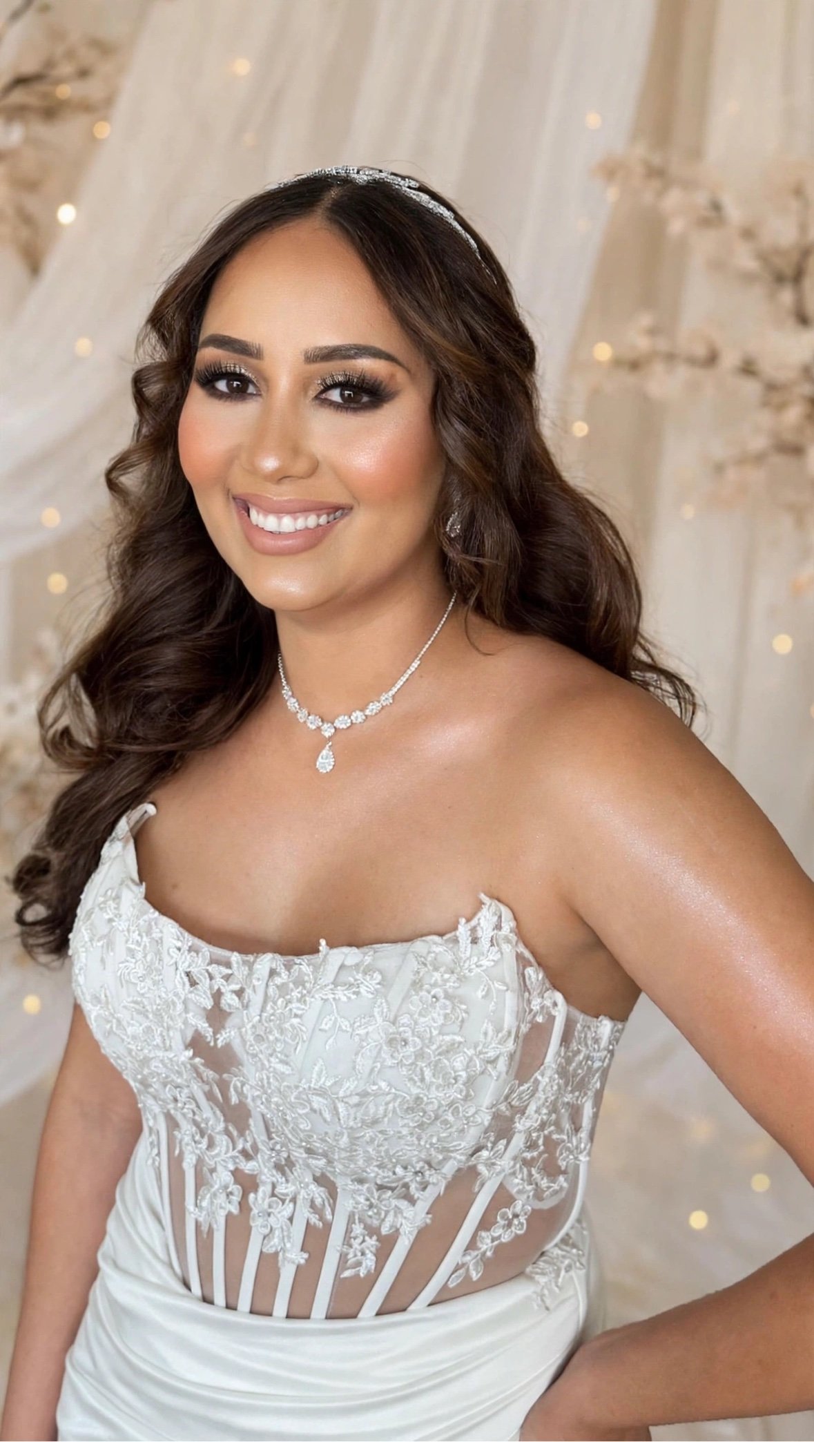 portfolio white corset bride smile - Glam By Duaa Bride in a white strapless lace corset gown with long dark waves and a crystal headband, smiling – Glam by Duaa